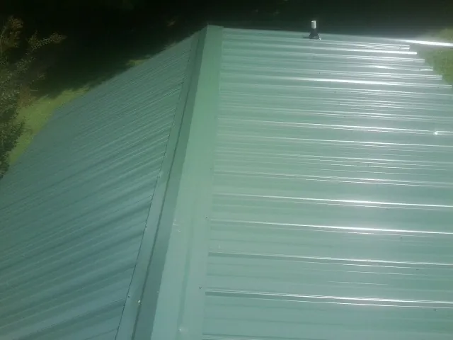 New green metal panels meeting at the ridge of a roof — Flat Roof Repair work by our crew in Franklin Park