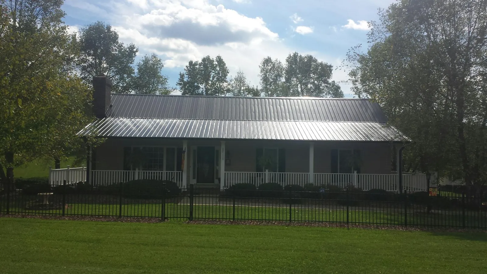Gray metal roof on a brick ranch with a full width front porch — Gutter Guard Installation work by our crew in Franklin Park